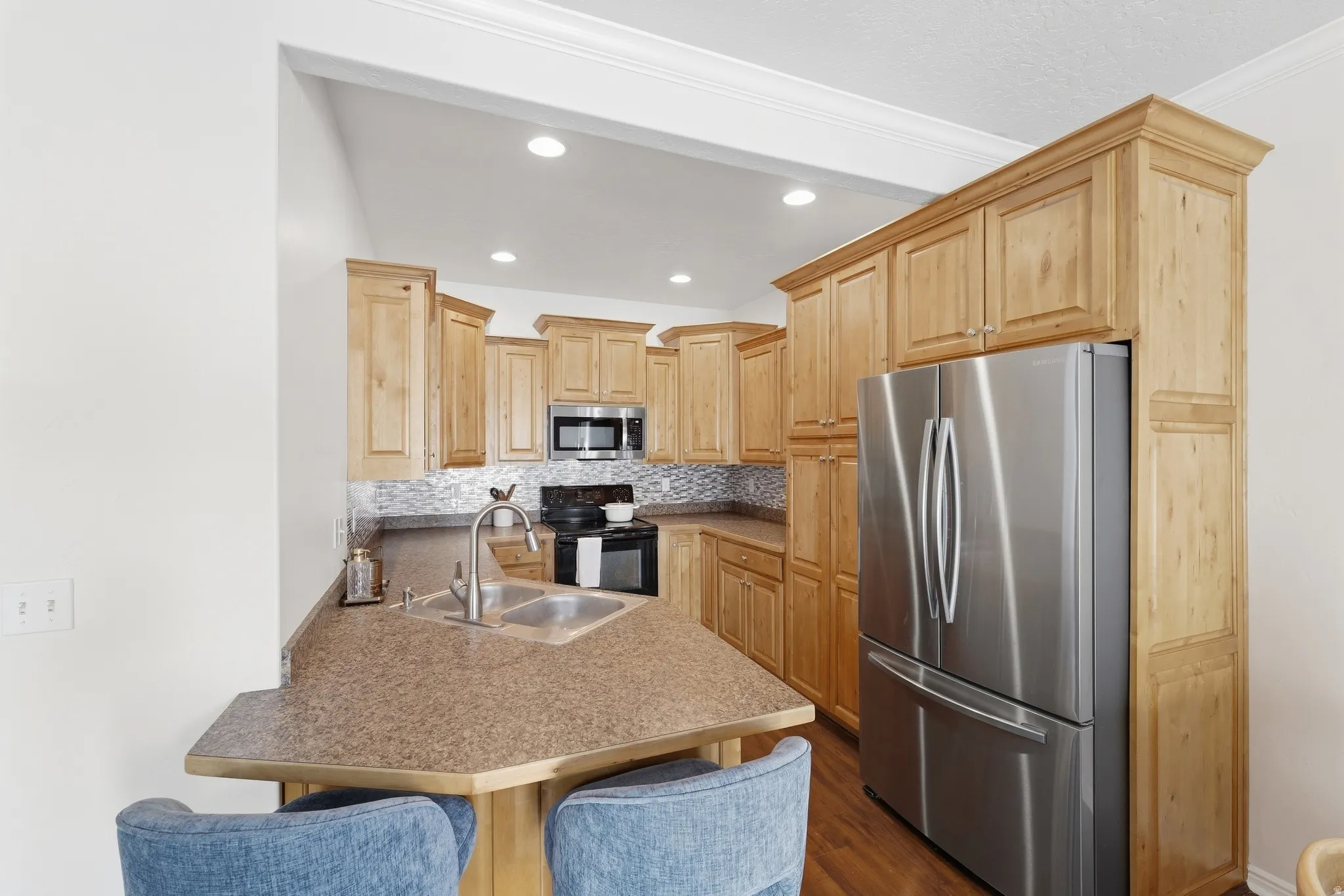 Kitchen featuring recessed lighting, extensive wood cabinetry, stainless steel appliances, and a tile backsplash