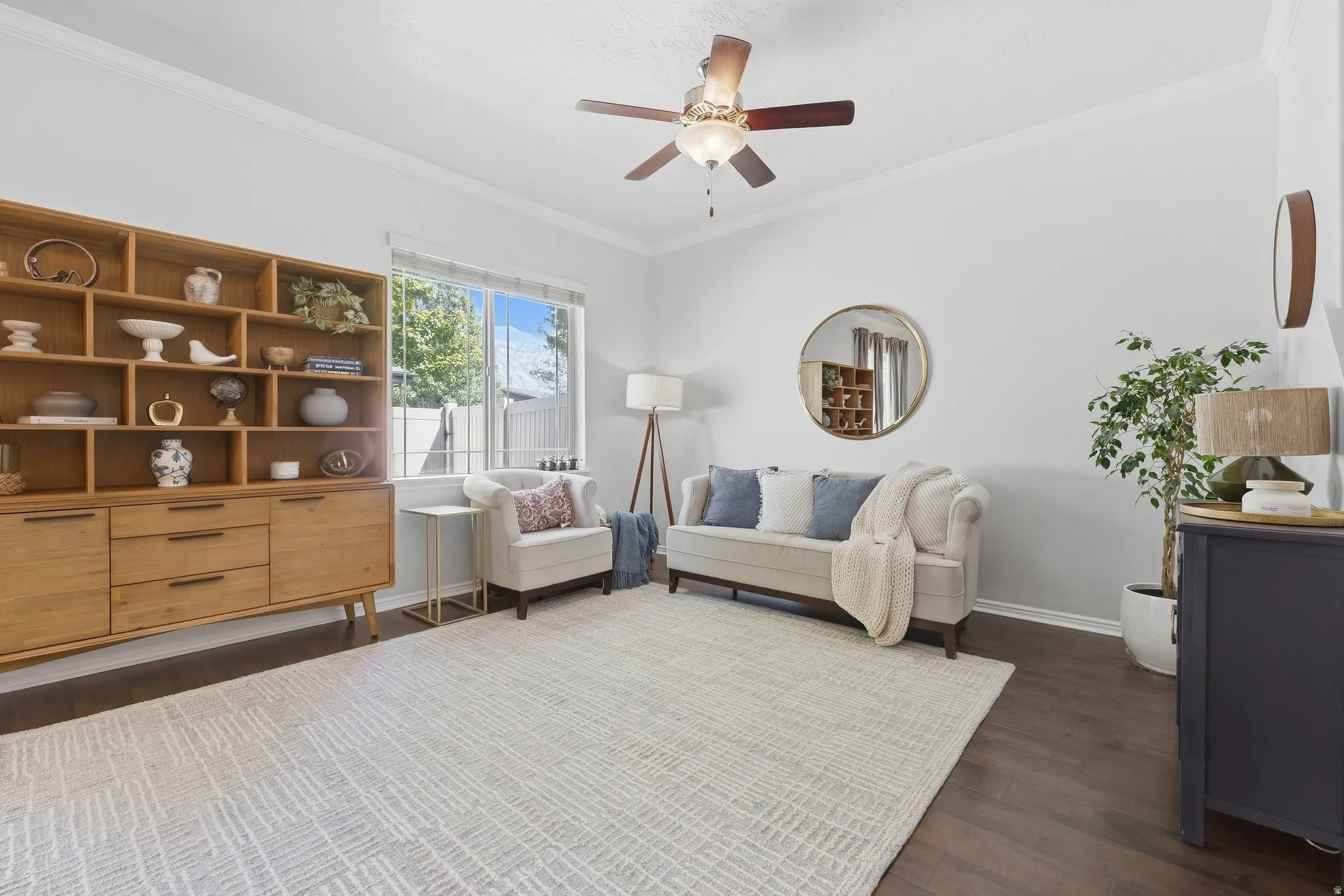 Wood-finish flooring, crown molding, and a ceiling fan with integrated lighting