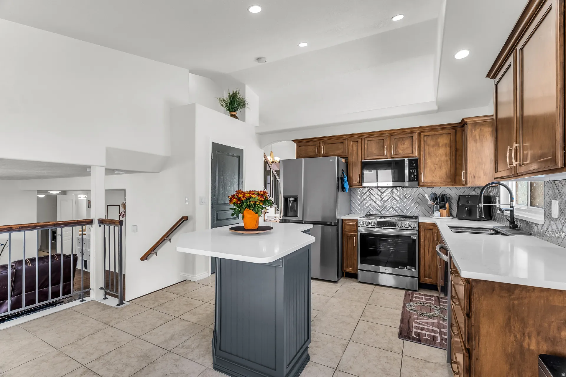 Kitchen featuring new stainless steel appliances, quartz countertops, upgraded herringbone tiled backsplash, vaulted ceilings with recessing lighting.