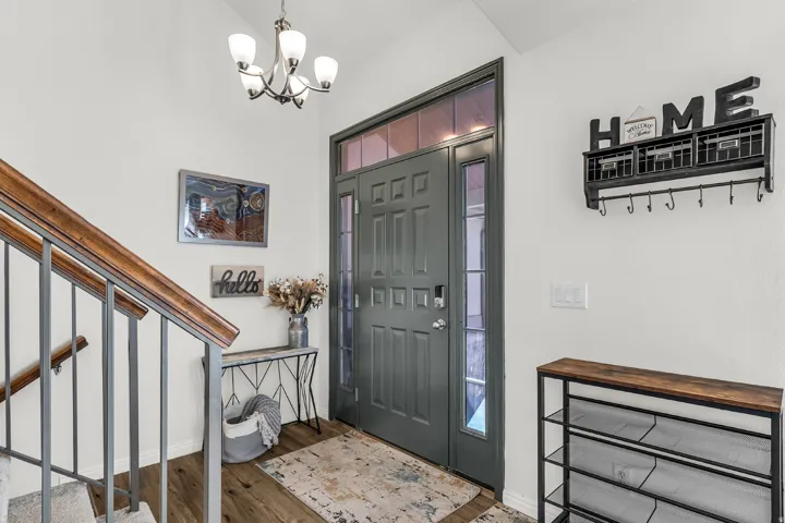 Entry door with side lite and transom window, updated LVP flooring and contemporary chandelier.