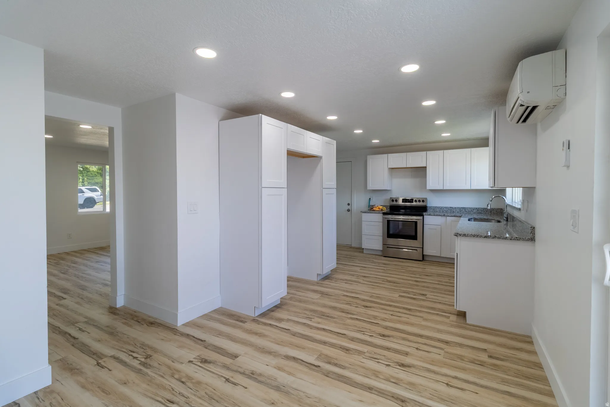 Kitchen featuring light wood-finish flooring, white cabinetry, recessed lighting, and stainless steel appliances