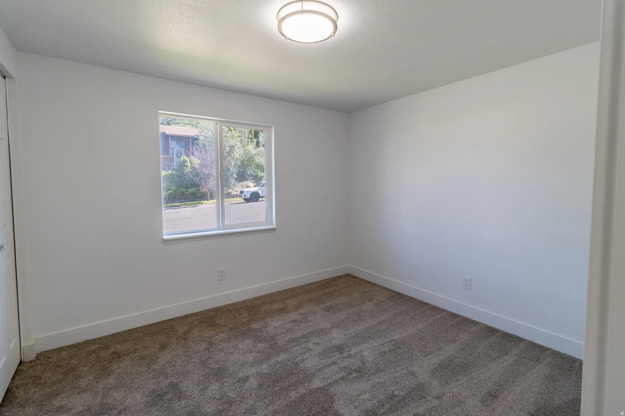 Neutral wall finishes, recessed window, flush-mount ceiling light, and carpeted flooring