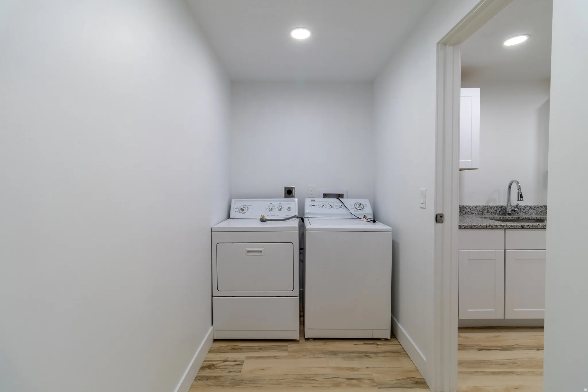 Dedicated laundry area with wood-finish flooring and recessed lighting