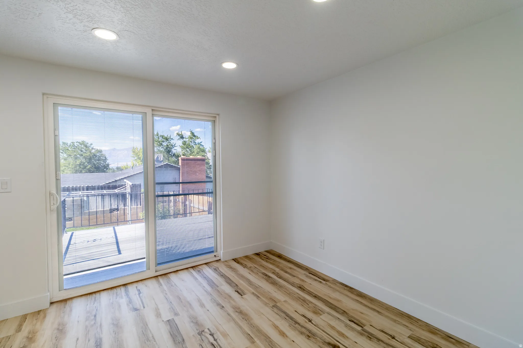 Wood-finish flooring, recessed lighting, and a sliding glass door providing exterior access