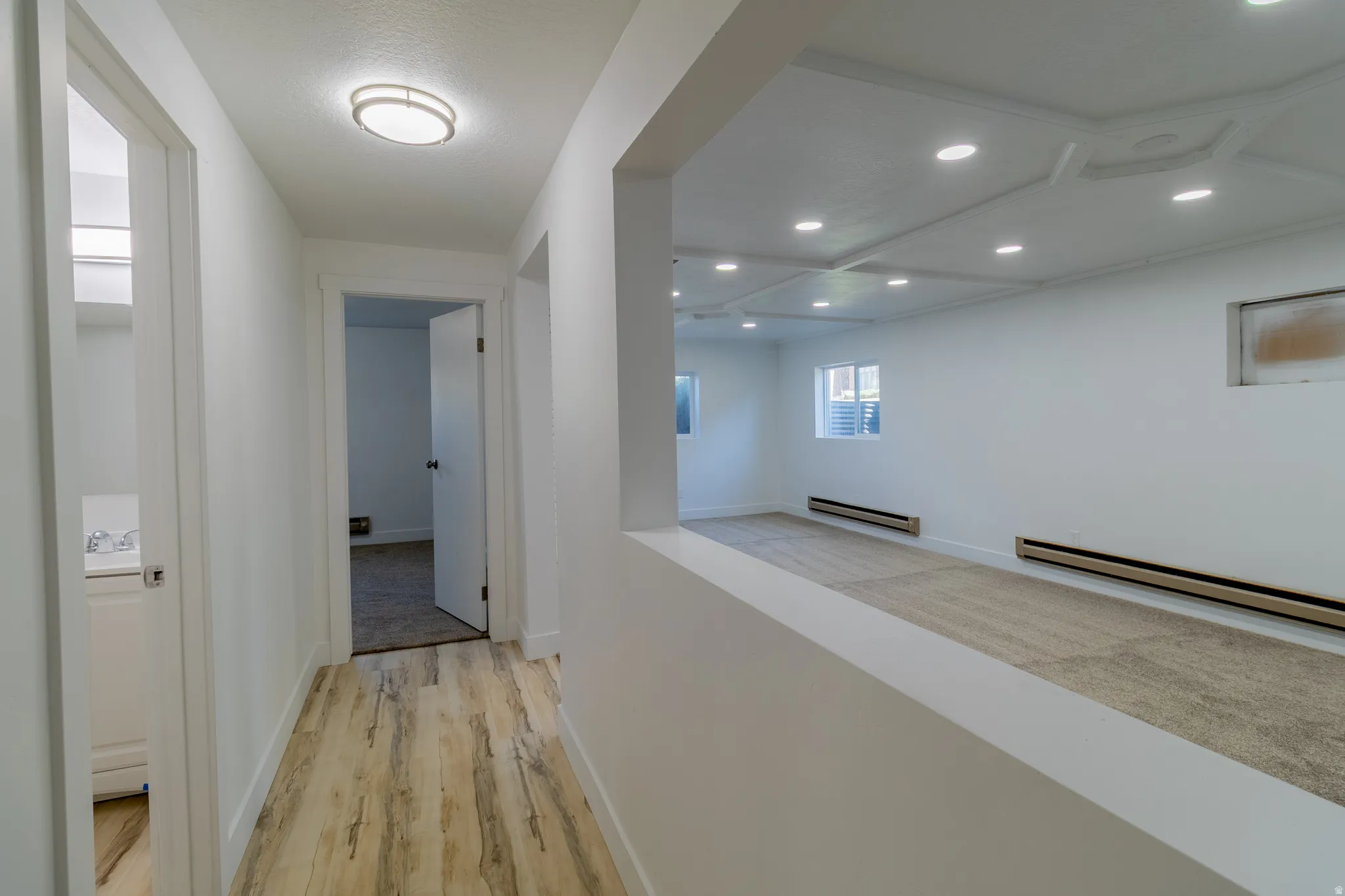 Hallway with wood-finish flooring, white walls, and a contemporary flush-mount ceiling light