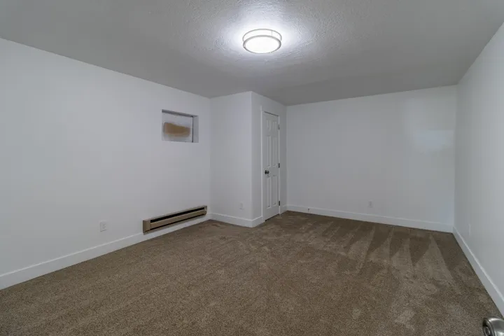 Neutral color palette, carpeted flooring, flush-mount ceiling light, white paneled door, baseboard trim