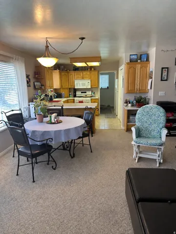 Open concept living area featuring a kitchen with wood-finish cabinetry, a white appliance package, and a breakfast bar