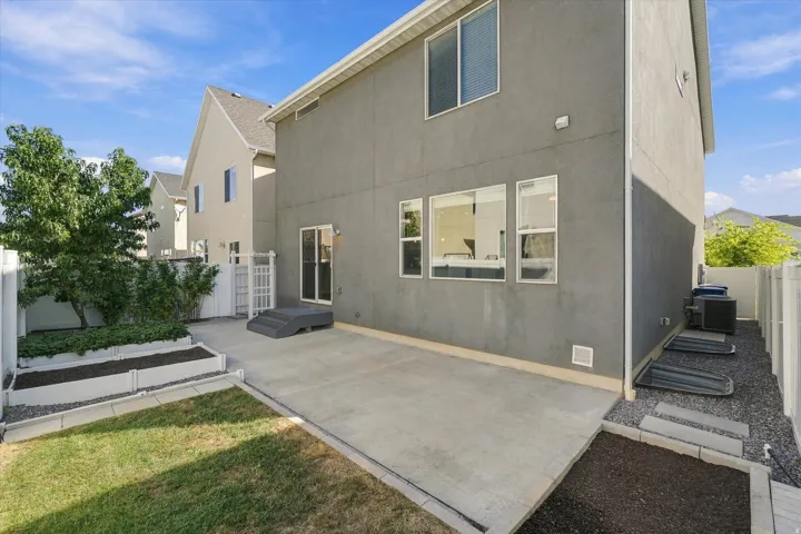 Private patio with concrete surfacing, white privacy fencing, raised garden beds, and ground-level windows