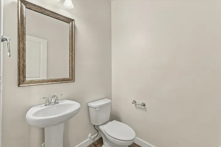 Pedestal sink with chrome-finish faucet, framed mirror, and wood-finish flooring