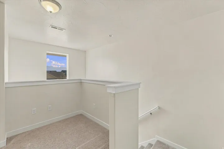 Carpeted flooring, white interior walls, and a window with a mountain backdrop