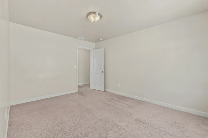 Neutral wall paint, plush carpet flooring, recessed lighting, and a white interior door