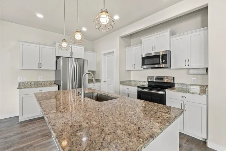 Kitchen featuring a large island, stainless steel appliances, white cabinetry, granite countertops, and wood-finish flooring