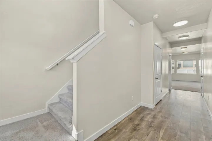 Wood-finish flooring, recessed lighting, and a carpeted staircase with a white handrail