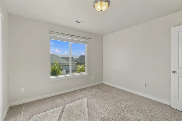 Neutral wall paint, carpeted flooring, a ceiling-mounted light fixture, and a window with blinds