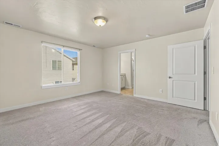 Carpeted room featuring a window with blinds, a flush mount light fixture, and panel doors