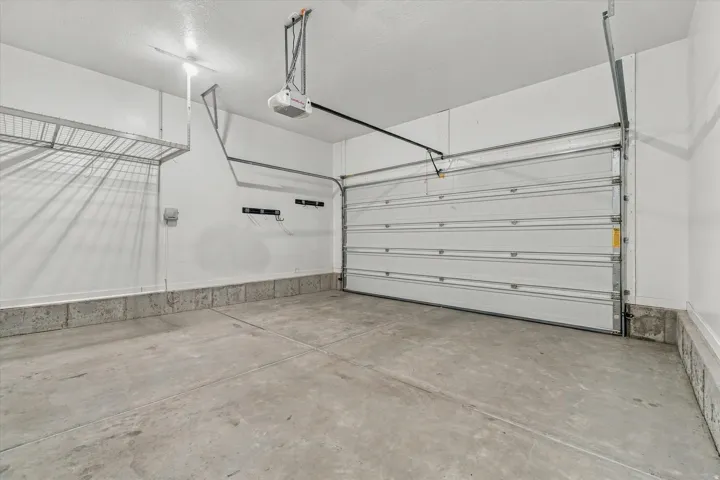 Attached garage featuring a concrete floor, automatic garage door opener, and integrated wire shelving