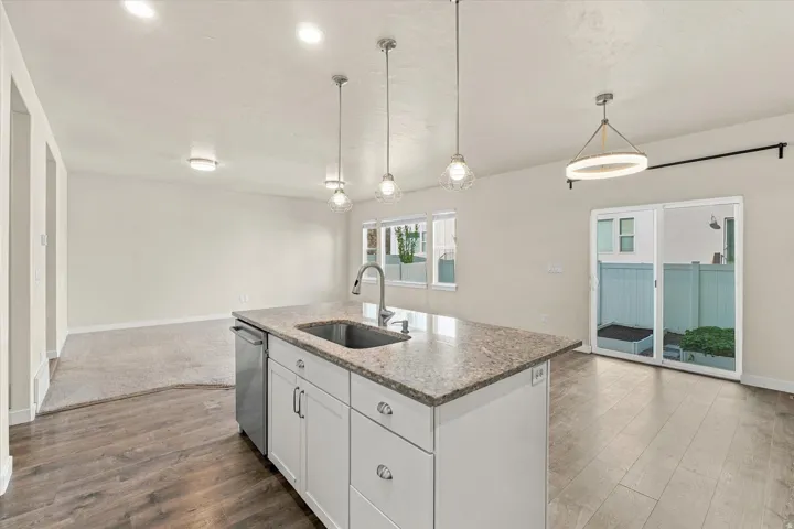 Kitchen island with granite-finish countertop, undermount stainless steel sink, and white cabinetry