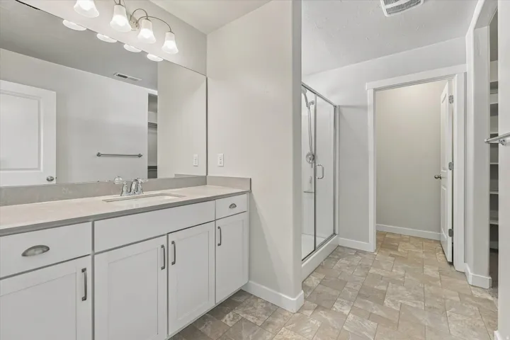 White vanity with ample storage, light-toned countertop, integrated sink, and modern chrome faucet