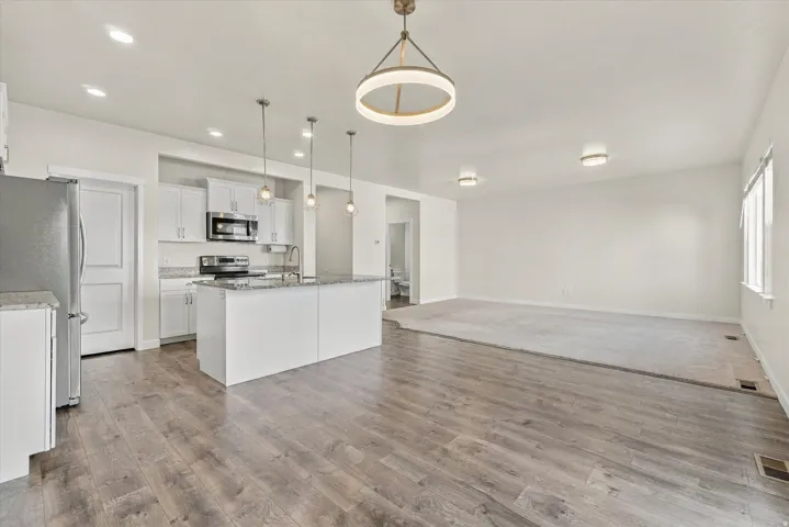 Open-concept living area featuring wood-finish flooring, recessed lighting, and a kitchen island with pendant lighting