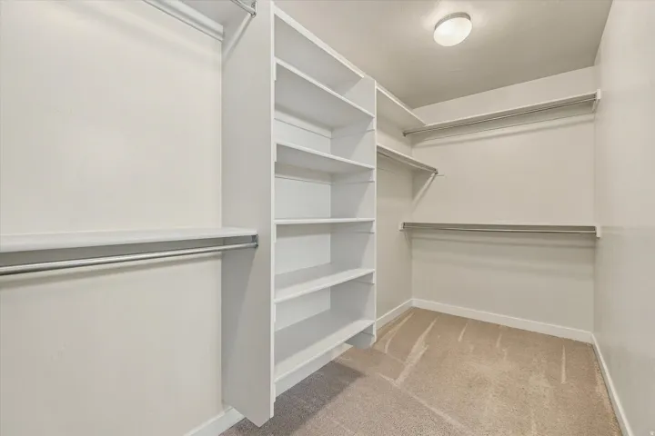 Walk-in closet with built-in shelving, multiple hanging rods, and recessed lighting