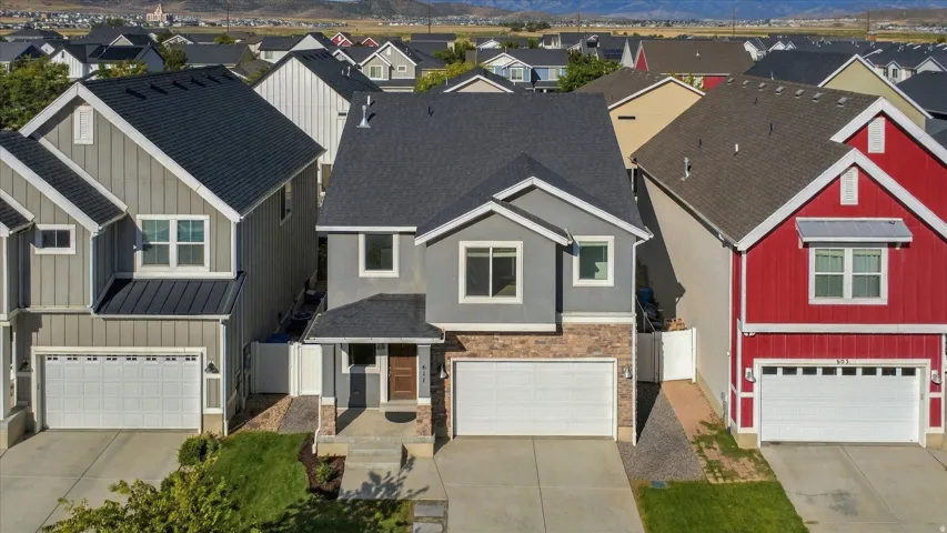 Two-story residence featuring a covered entry porch, dark shingle roof, and an attached two-car garage