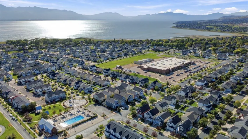 Aerial perspective showcasing a residential community with abundant housing, a large body of water, and distant mountains