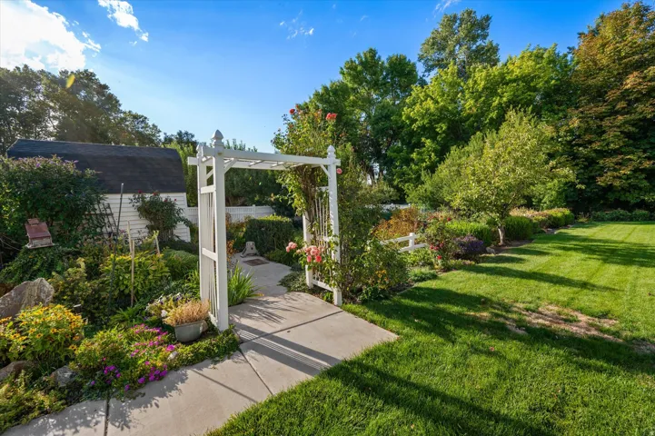 Expansive green lawn with mature trees and a white arbor entryway