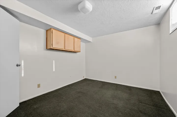 Recessed wall cabinetry, overhead ceiling light fixture, and textured ceiling