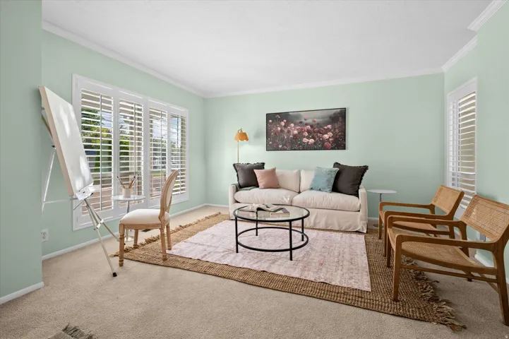 Wall-to-wall carpeting, crown molding, and a large window with white plantation shutters