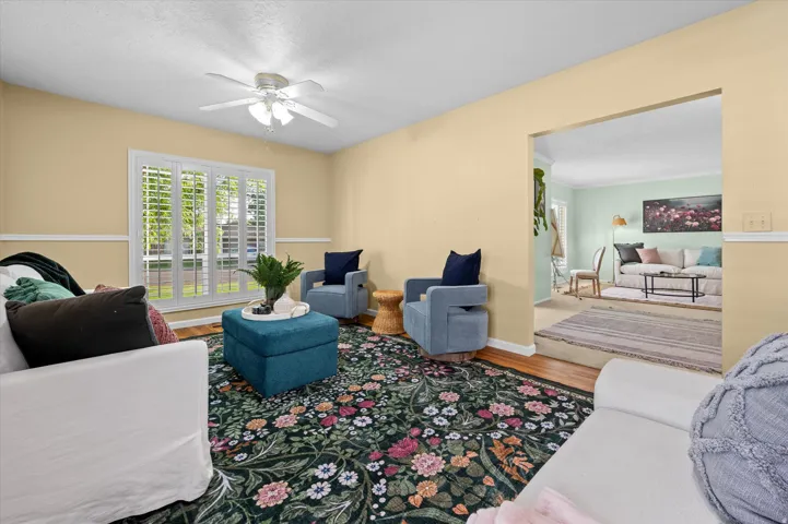Hardwood flooring, crown molding, a ceiling fan with integrated lighting, and a window with plantation shutters