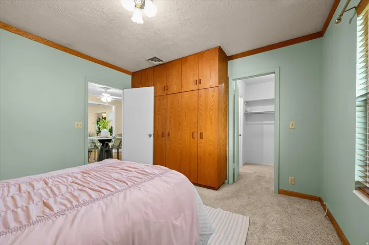 Built-in wood-finish cabinetry, neutral carpeting, and a window with blinds
