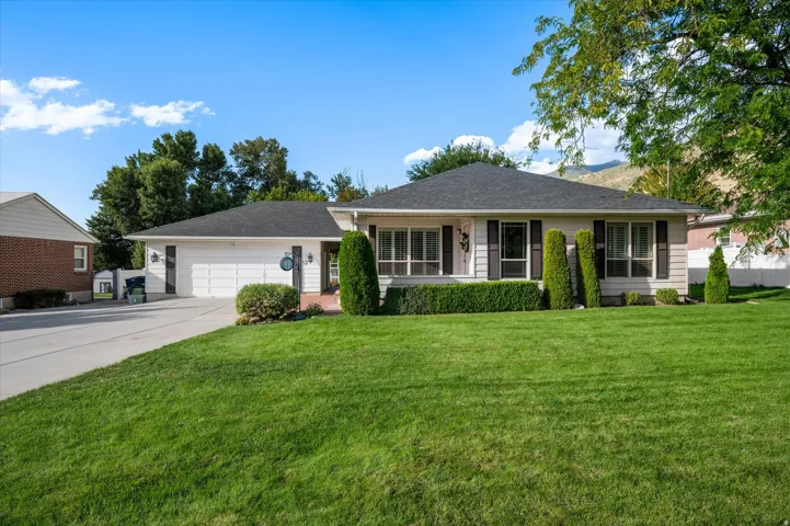 Expansive front lawn, attached two-car garage, mature trees, and landscaping