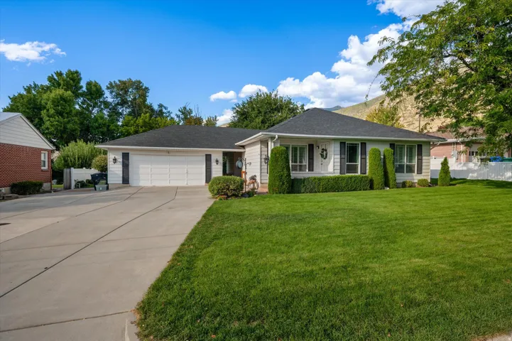 Single-story residence featuring a two-car garage, concrete driveway, and front lawn