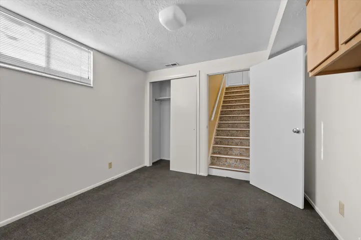 Plush gray carpeting, white walls, and a window with blinds