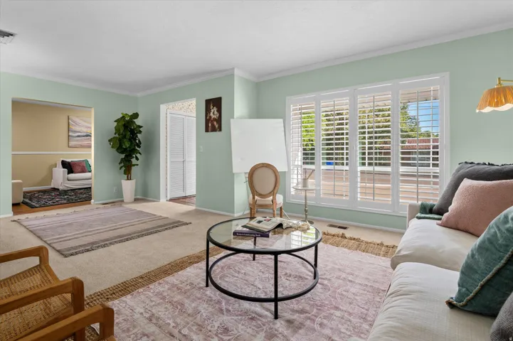 Expansive window with white plantation shutters, light green painted walls, and ceiling crown molding