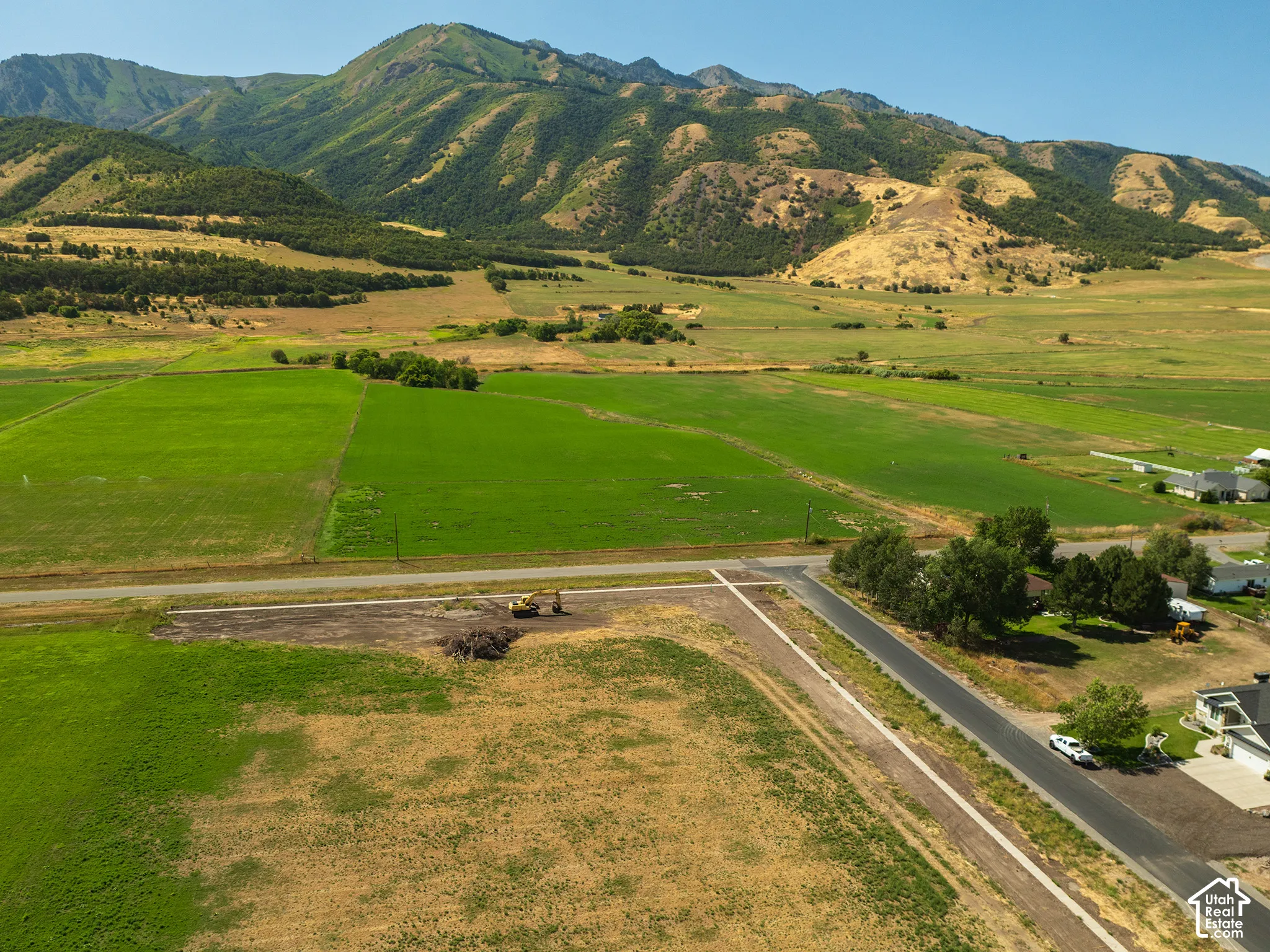 Expansive undeveloped land with a paved road and mountain backdrop