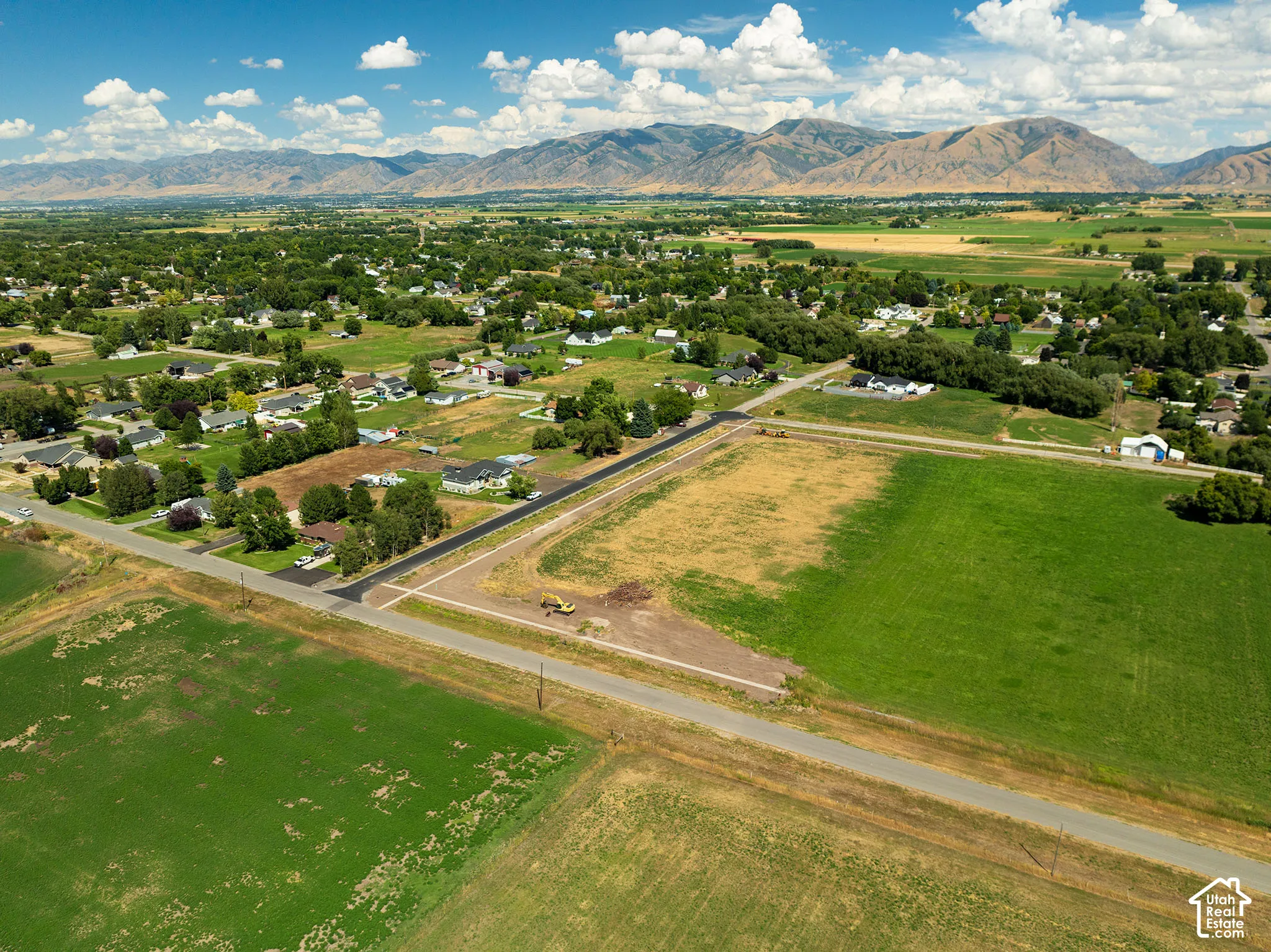 Expansive agricultural land with surrounding residential areas and distant mountains