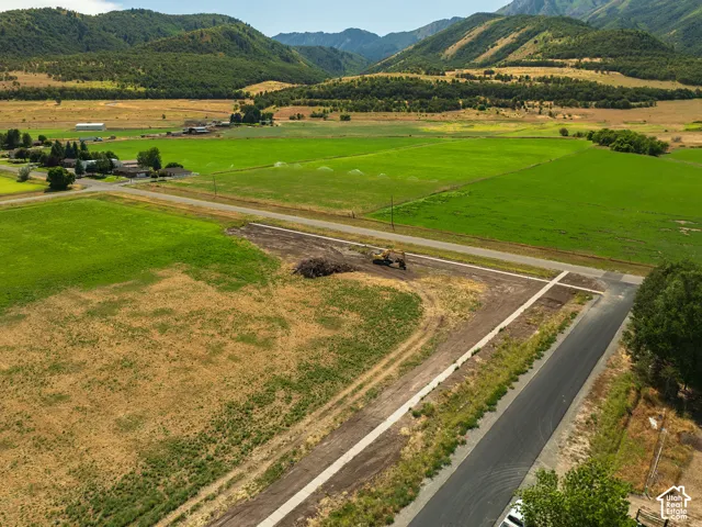 Paved road access, mountainous backdrop, and expansive green fields