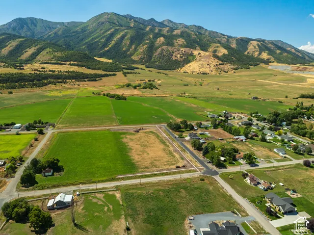 Expansive green fields, paved roads, and distant mountain backdrops