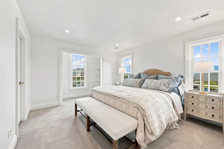 Recessed lighting, light-toned carpeting, multiple windows, built-in shelving, and a paneled door