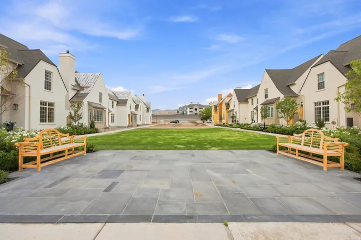 Expansive central green space featuring a manicured lawn, bordered by stone-paved patios