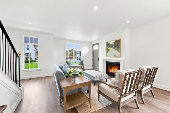 Recessed lighting, wood-finish flooring, white trim, and a fireplace with a white mantel and surround