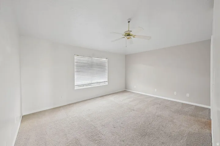 Wall-to-wall carpeting with a neutral finish, ceiling fan, and window with horizontal blinds