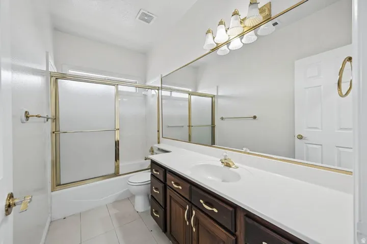 Bathroom featuring a vanity with dark wood-finish cabinetry, a large integrated countertop and sink, and a wall-mounted mirror