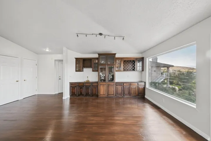 Wood-finish flooring throughout, featuring a built-in wet bar with wood cabinetry and a wine rack