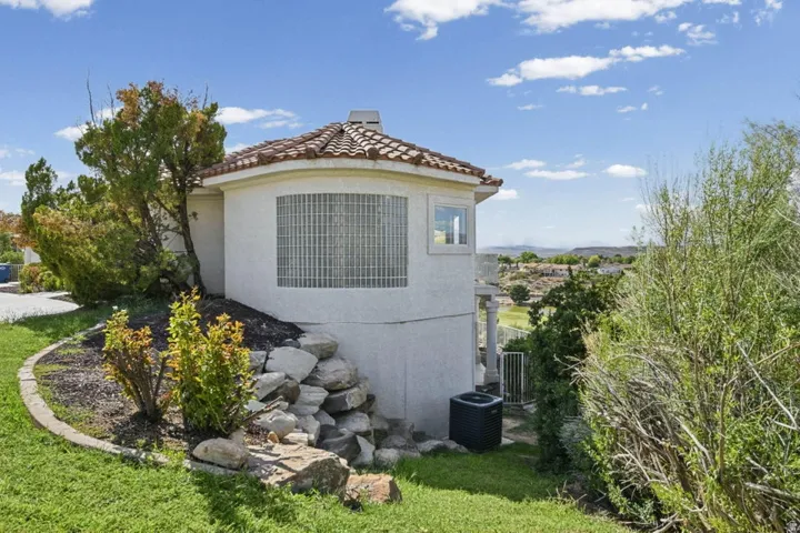 Stucco exterior with a tiled roof, curved architectural element, glass block window, and landscaping