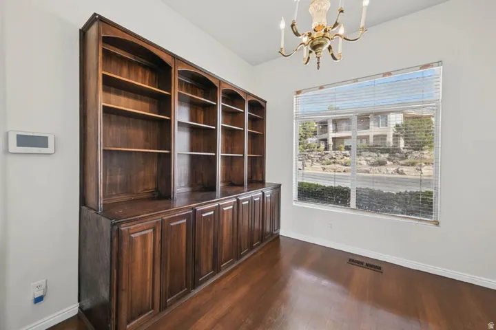 Built-in wood cabinetry with open shelving and closed storage, wood-finish flooring, and a brass chandelier