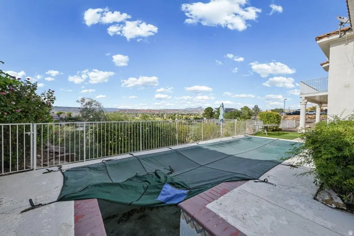 Concrete patio with a covered pool and surrounding white metal fencing