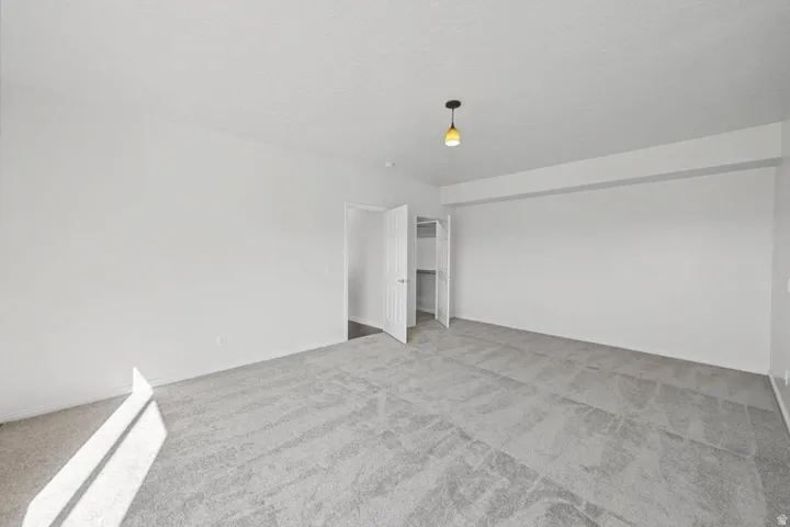 Neutral-toned carpeting, white walls, and a built-in closet with shelving