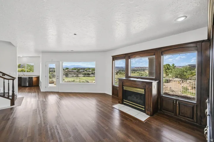 Hardwood-finish flooring, a built-in fireplace with a tile hearth, and dark wood-framed windows